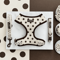 Dog harness, leash, and collar set with polka dot pattern on a marble surface.