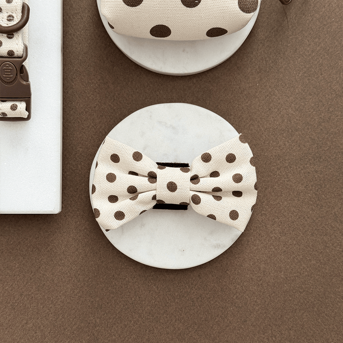 Polka dot bow tie on a marble surface with a brown background
