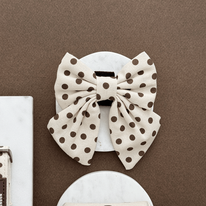 Polka dot bow on a white surface with a brown background