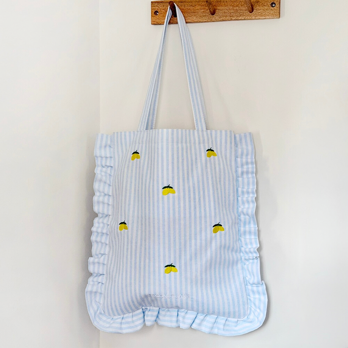 Blue and white striped tote bag with ruffles and lemon print detailing.