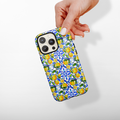 Hand holding a Cocopup London Amalfi Lemon tough phone case with blue floral pattern on white background.