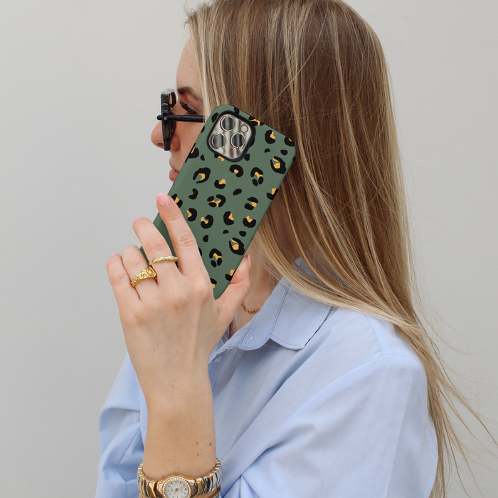 Woman holds an iPhone with a khaki leopard print tough phone case near her face.
