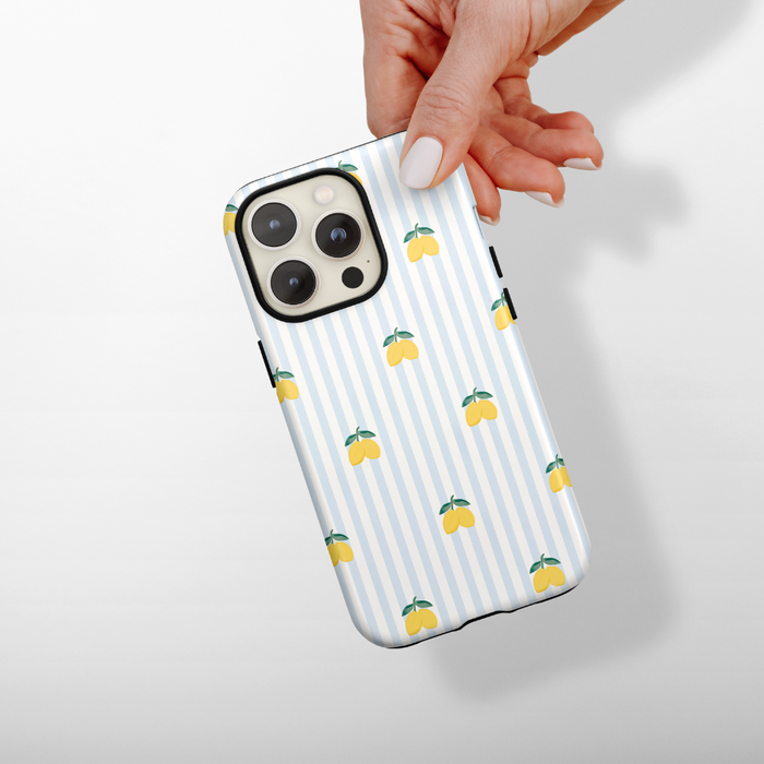Hand holding a Cocopup London Tough Phone Case with blue stripes and lemon pattern.