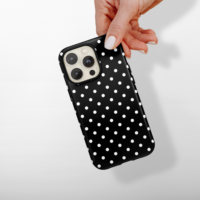 Hand holding a Cocopup London tough phone case with a black-and-white polka dot pattern.