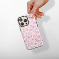 Hand holding a Cocopup London phone case featuring pastel dinosaur and volcano pattern on a white background.