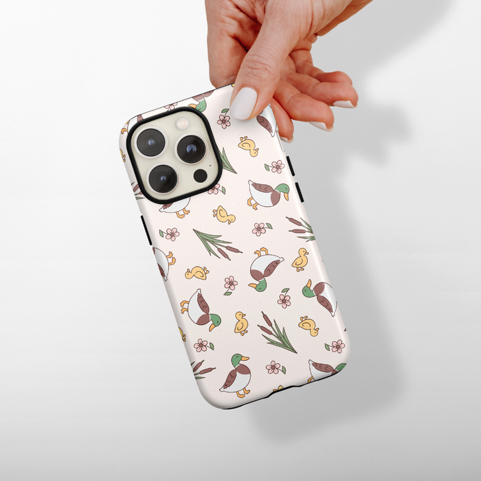 Hand holding a Cocopup London phone case with a white background and playful pups, plants, and flowers pattern.
