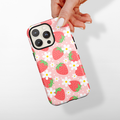 Hand holding Cocopup London tough phone case with a strawberry and white flower pattern on a light background.