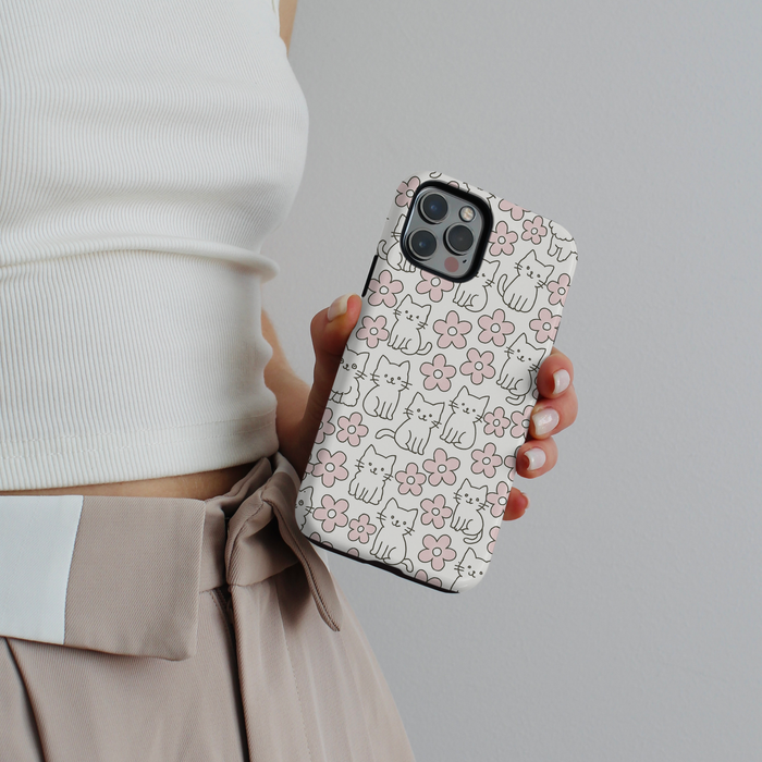 Cocopup London Tough Phone Case with playful cat and flower pattern on a pink background, held in someones hand.