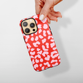 Hand holding a Cocopup London tough phone case in red and pink leopard print against a light background.