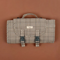 Folded Cocopup London plaid travel mat with buckle straps and handle, shown on a brown surface.