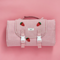 Pink gingham picnic bag with a small strawberry embroidered detail.