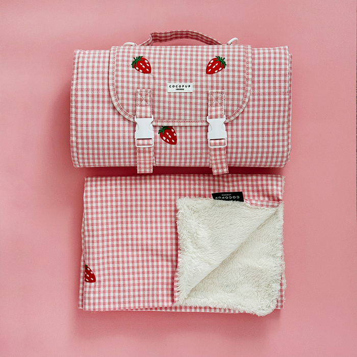 Strawberry-patterned Cocopup London travel mat and blanket set, shown folded and open on a pink background.