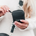 Black Cocopup London Treat Pouch with leopard-print strap, held by woman in a white sweater.