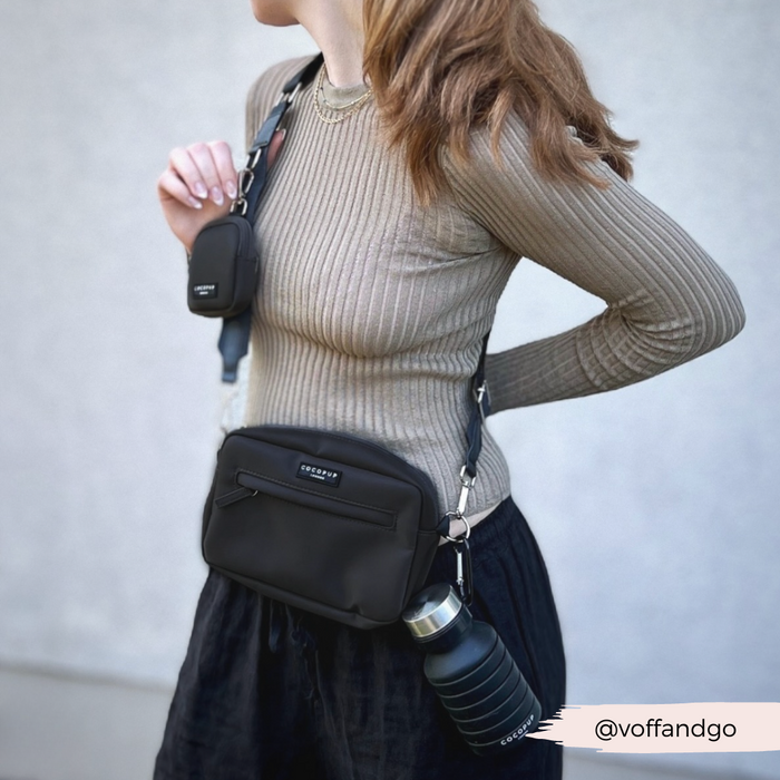 Woman in ribbed top, black skirt, crossbody bag, holding water bottle and black Cocopup London Treat Pouch.
