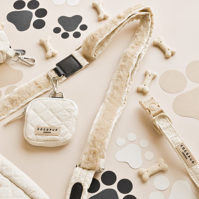 Cream quilted Cocopup London treat pouch on background with paw print and bone patterns.