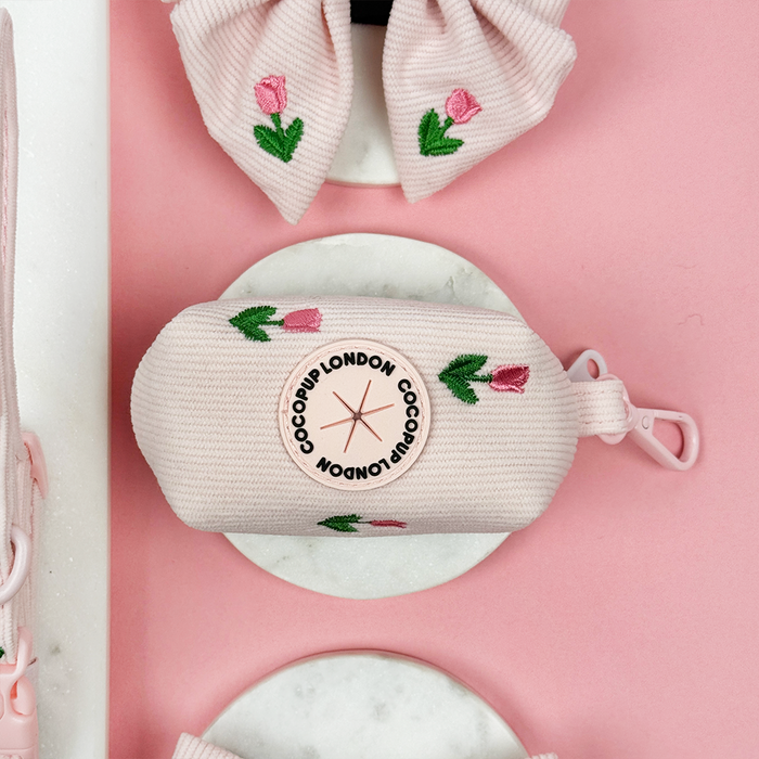 Pink dog poop bag holder with embroidered tulip design.