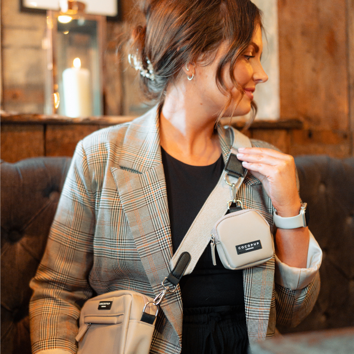 Woman in a plaid blazer sits with a brown Cocopup London tweed bag strap on her crossbody bag.