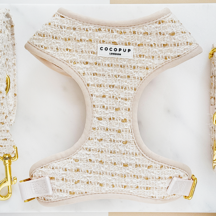 Cream and gold tweed dog harness with adjustable neck, laid flat on a white background.