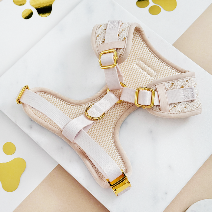 Vanilla textured tweed adjustable neck harness with gold hardware on a white marble surface with gold accents.