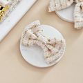 Vanilla textured tweed bow tie by Cocopup London clipped on a round white marble tray.