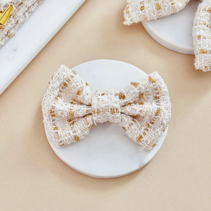 Vanilla-colored textured tweed bow tie on a round white marble tray.