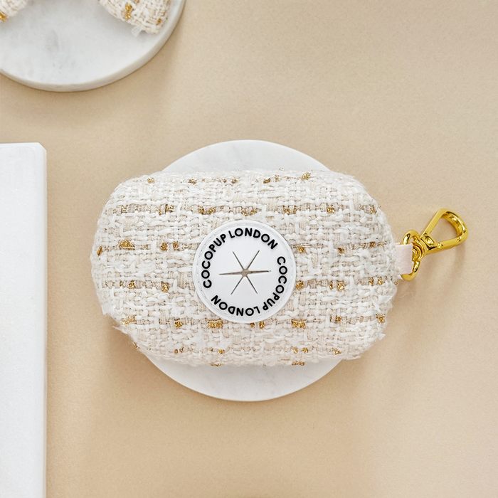 Vanilla textured tweed poop bag holder with gold clasp, displayed on a beige background.