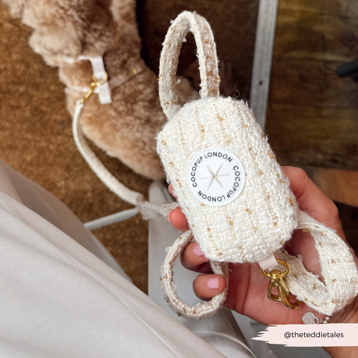 Vanilla textured tweed Cocopup London poop bag holder with gold clip, held in a hand.