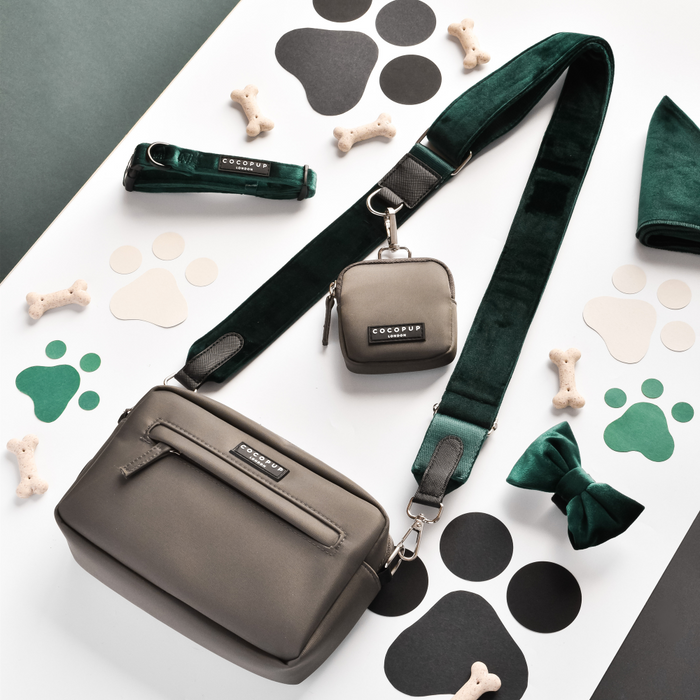 Forest green velvet bag strap from Cocopup London shown with gray pet accessories on a paw print patterned surface.