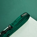 Forest green velvet dog lead with a black clasp, rolled neatly on a white surface.