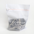 White mesh Cocopup London laundry bag with zipper closure.