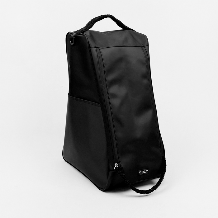 Black Cocopup London welly boot bag stands upright with a top handle on a white background.