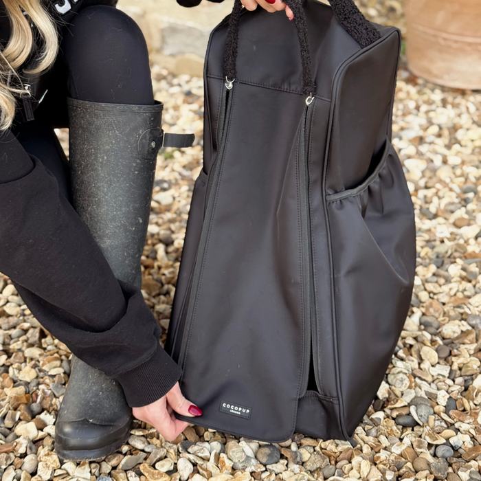 Black Cocopup London welly boot bag and black boots on gravel.