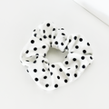 White fabric scrunchie with black polka dots.