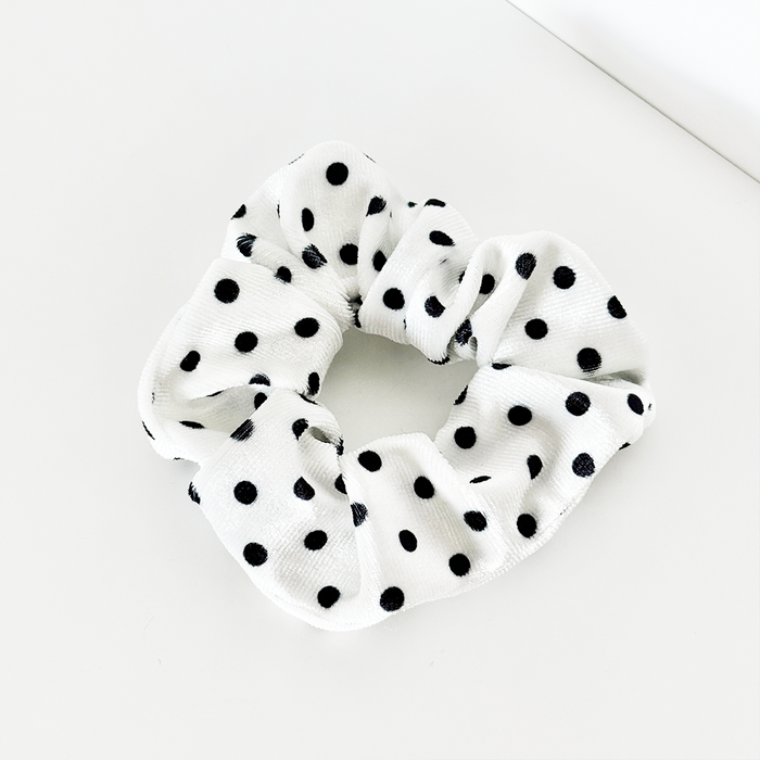 White fabric scrunchie with black polka dots.